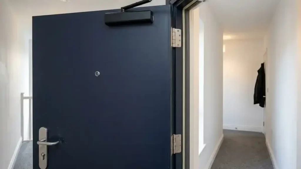 Navy flat front door with an automatic door closer, a fire door that must not be altered in a UK rental